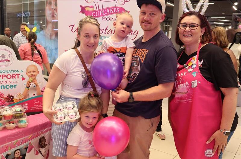 A family standing in front of a pink banner next to each other
