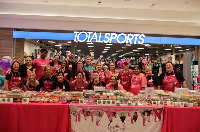 A group of ladies and gentleman standing in front of cupcake stalls.