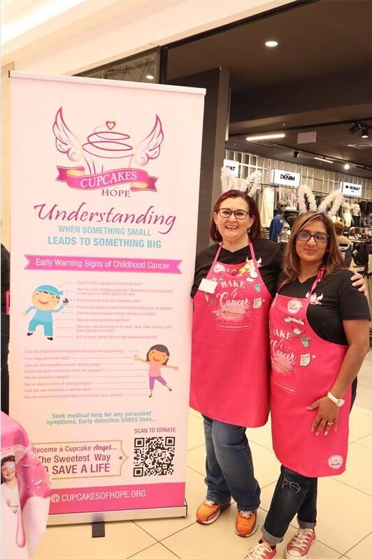 Two ladies wearing pink aprons standing next to each other