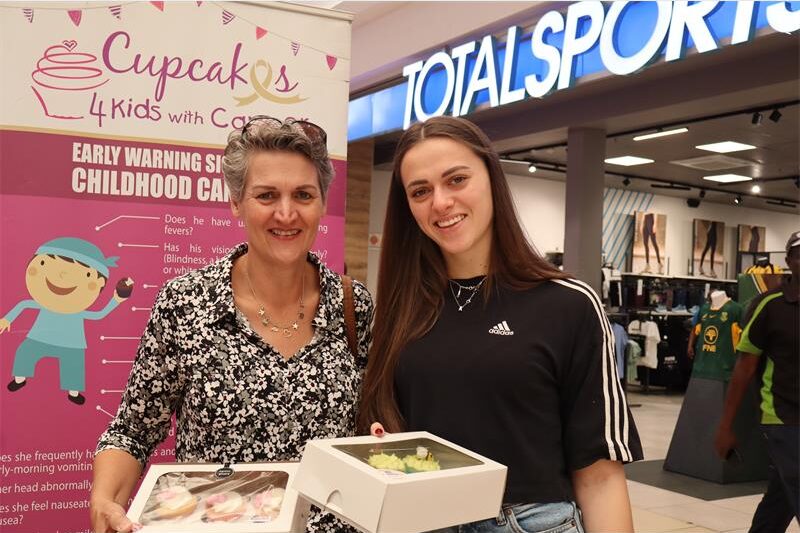 Two ladies holding cupcakes wearing black and white