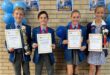 Four children, two boys and two girls holding certificates