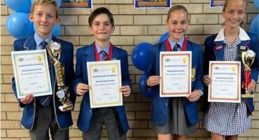 Four children, two boys and two girls holding certificates