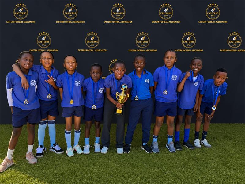 Group of boys in blue uniforms, holding a trophy