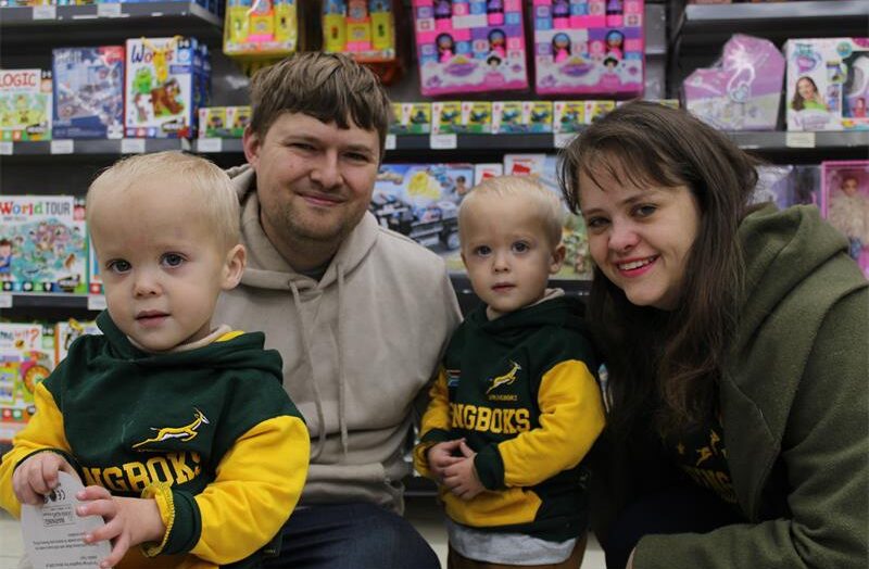 Man and woman hold twin boys wearing Springbok shirts