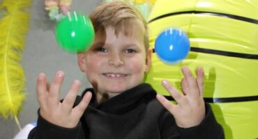 Boy smiling while throwing balls into the air
