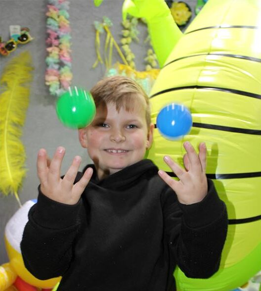Boy smiling while throwing balls into the air