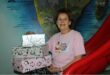 Woman wearing a pink shirt, sitting on a red slide holding gift boxes