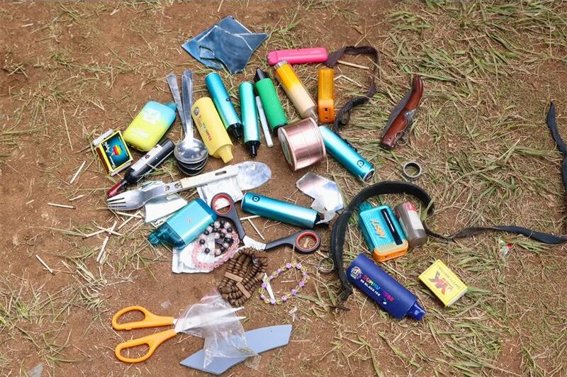 Various items including vapes, match boxes and a knife on the ground