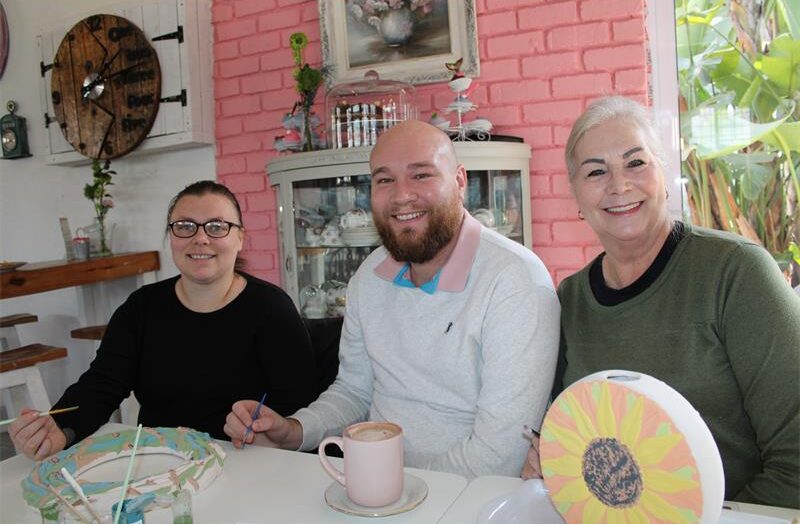 Three people, two women and a man painting ceramics