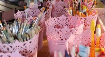 Pink containers holding pencils and paint brushes