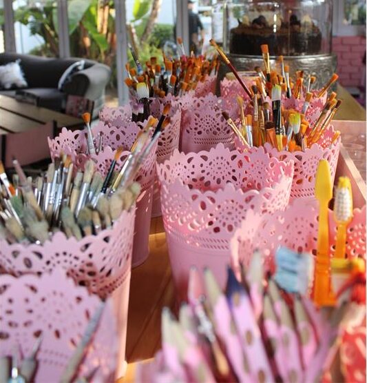 Pink containers holding pencils and paint brushes