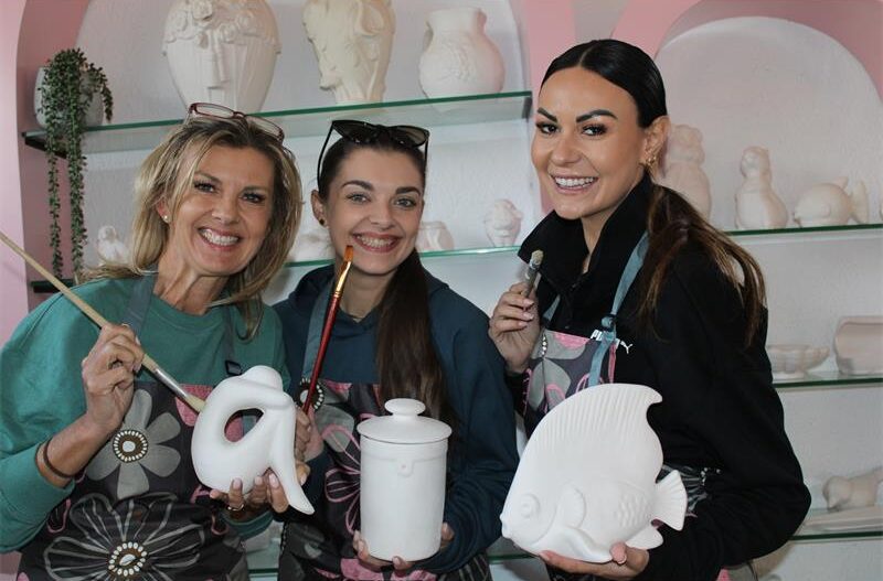 Three women holding unpainted ceramics