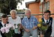 Twee jong seuns hou blomme aan bejaarde man en vrou