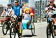 Cyclist with a teddy bear on the back of a bike, taking part in a race.