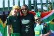 Two women and a girl standing in front of a South African flag