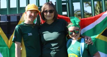 Two women and a girl standing in front of a South African flag