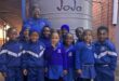 Educator stands with a group of uniformed children at a water tank