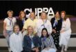 Group of women sitting in front of letters that spell CUPPA