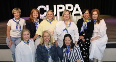 Group of women sitting in front of letters that spell CUPPA