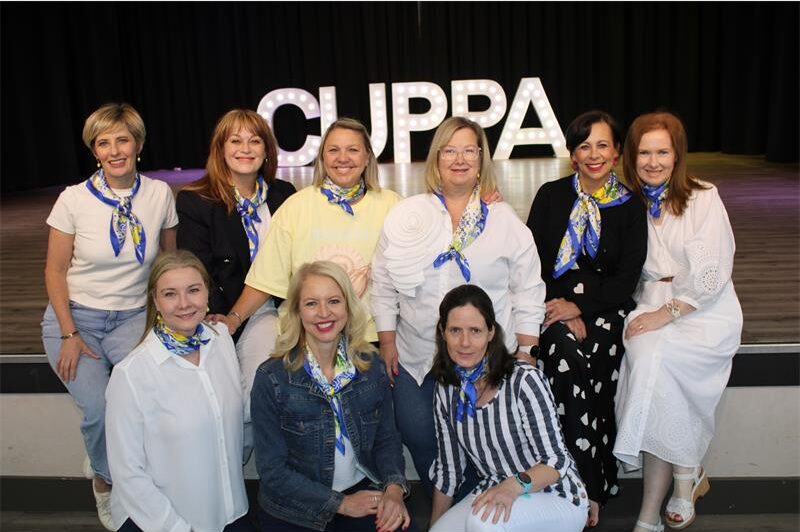 Group of women sitting in front of letters that spell CUPPA