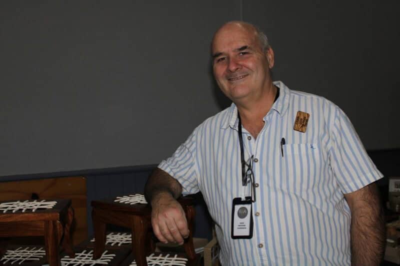 Older man leaning on wooden stools