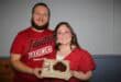 Man and woman dressed in red holding a box