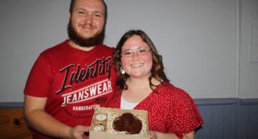 Man and woman dressed in red holding a box