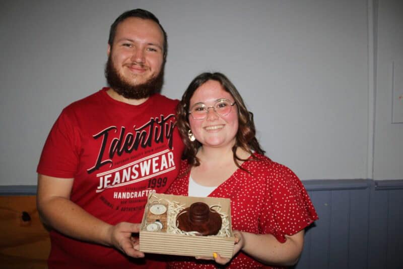 Man and woman dressed in red holding a box