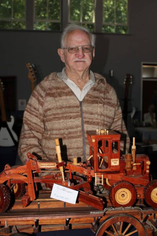 Elderly man standing with a wooden road scraper