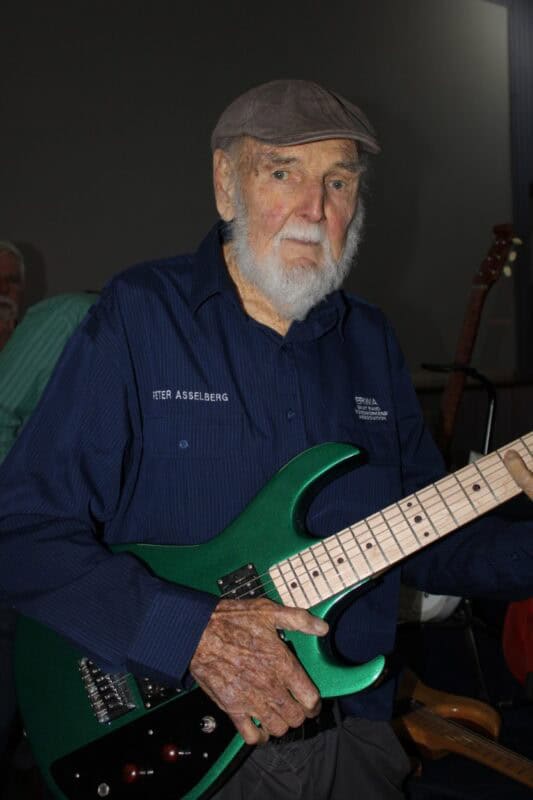 Elderly man holding a green guitar