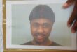Picture of a black man wearing a beaning with a black hand resting on the edge of the photo