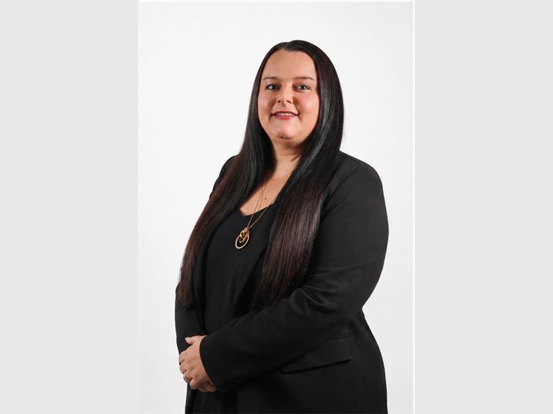 A white woman with long dark hair dressed in black.