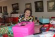 An elderly woman surrounded by gift wrapped boxes