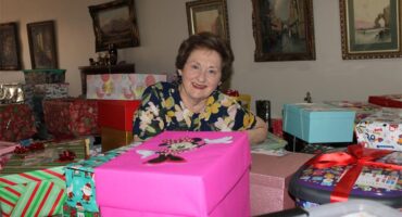 An elderly woman surrounded by gift wrapped boxes