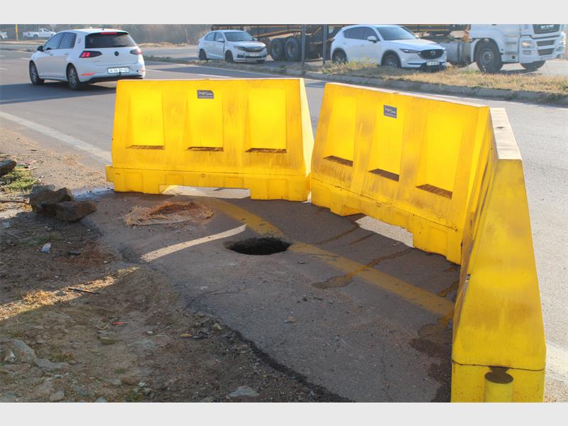 Yellow plastic cordons around a hole in the ground