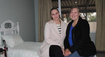 Two white women sitting on a bed