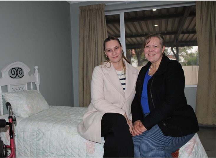 Two white women sitting on a bed