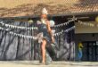 Black girl walking on a stage with a dress made of black bags
