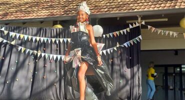 Black girl walking on a stage with a dress made of black bags