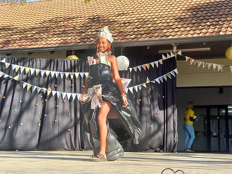 Black girl walking on a stage with a dress made of black bags