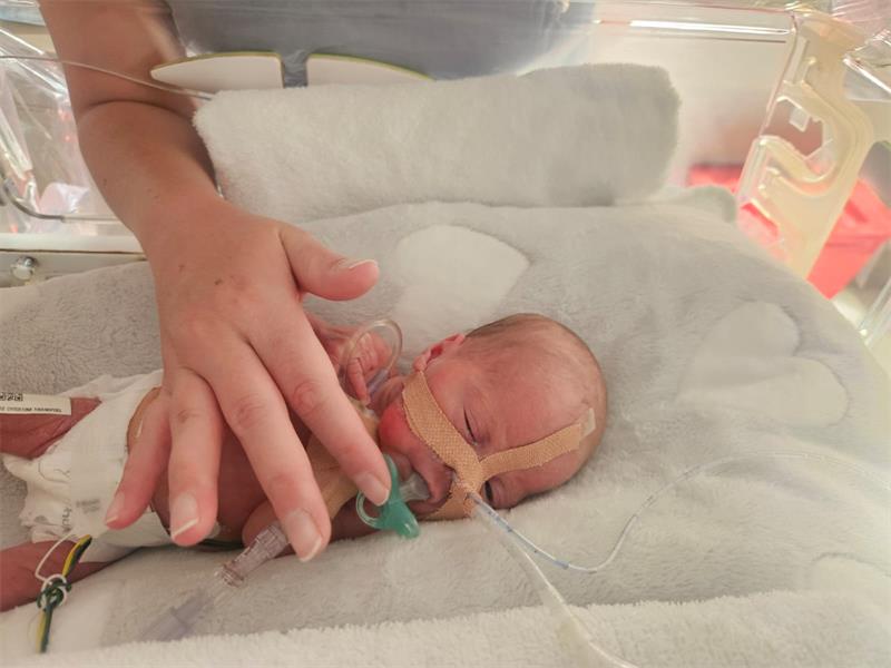 A baby in an incubator with a tube attached to it.
