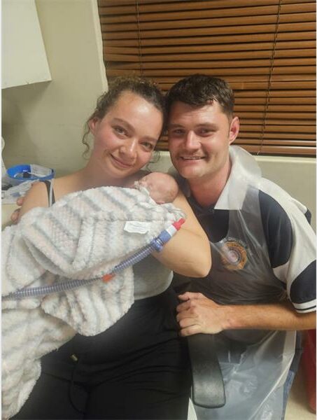 A man and woman holding a baby in a hospital room.