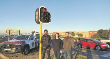 Three people standing next to a traffic light.