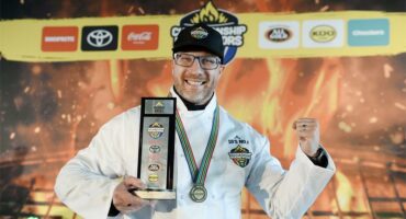 A man in a chef's outfit holding a trophy.