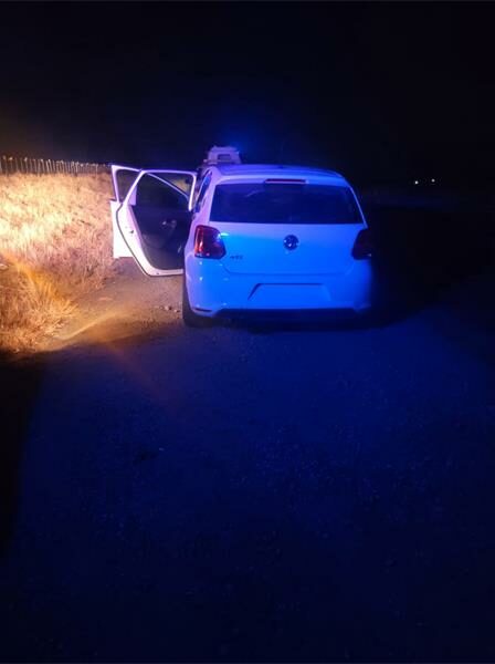 A police car parked in the dark on a road.