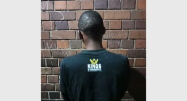 A man wearing a black shirt with the words "KINGS" on it.