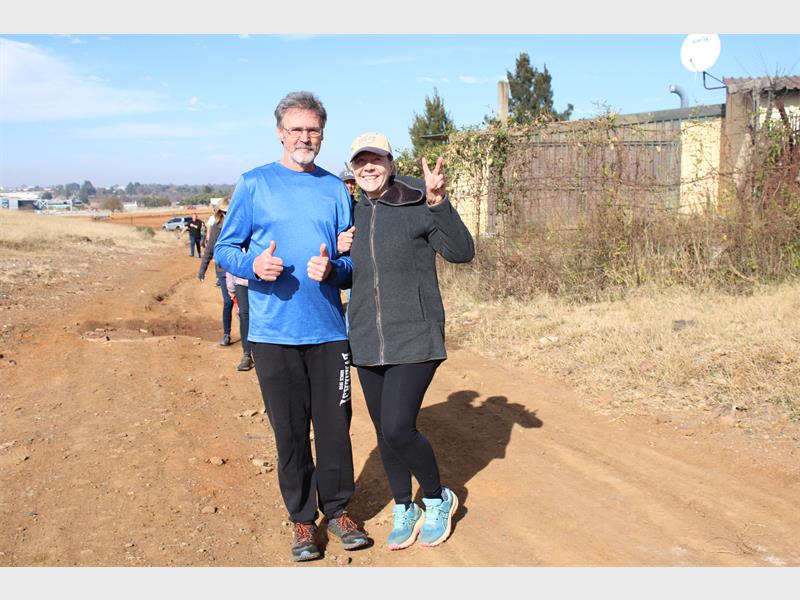 A man and woman standing on a dirt road.