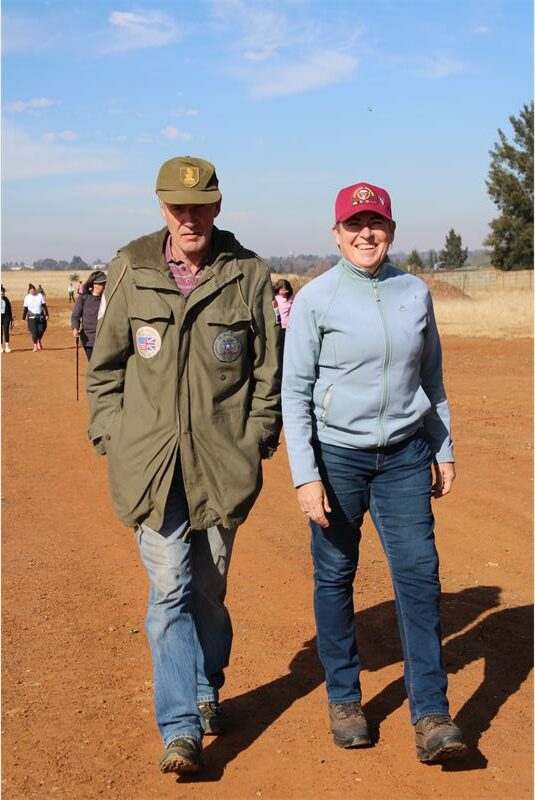 Two people standing on a dirt road.