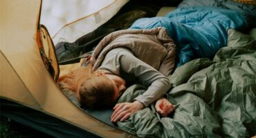 A person sleeping in a tent by a lake.