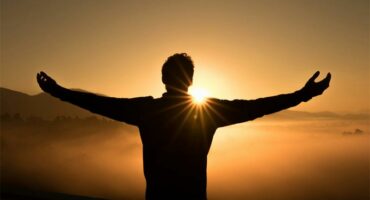 Man with arms outstretched at sunset.